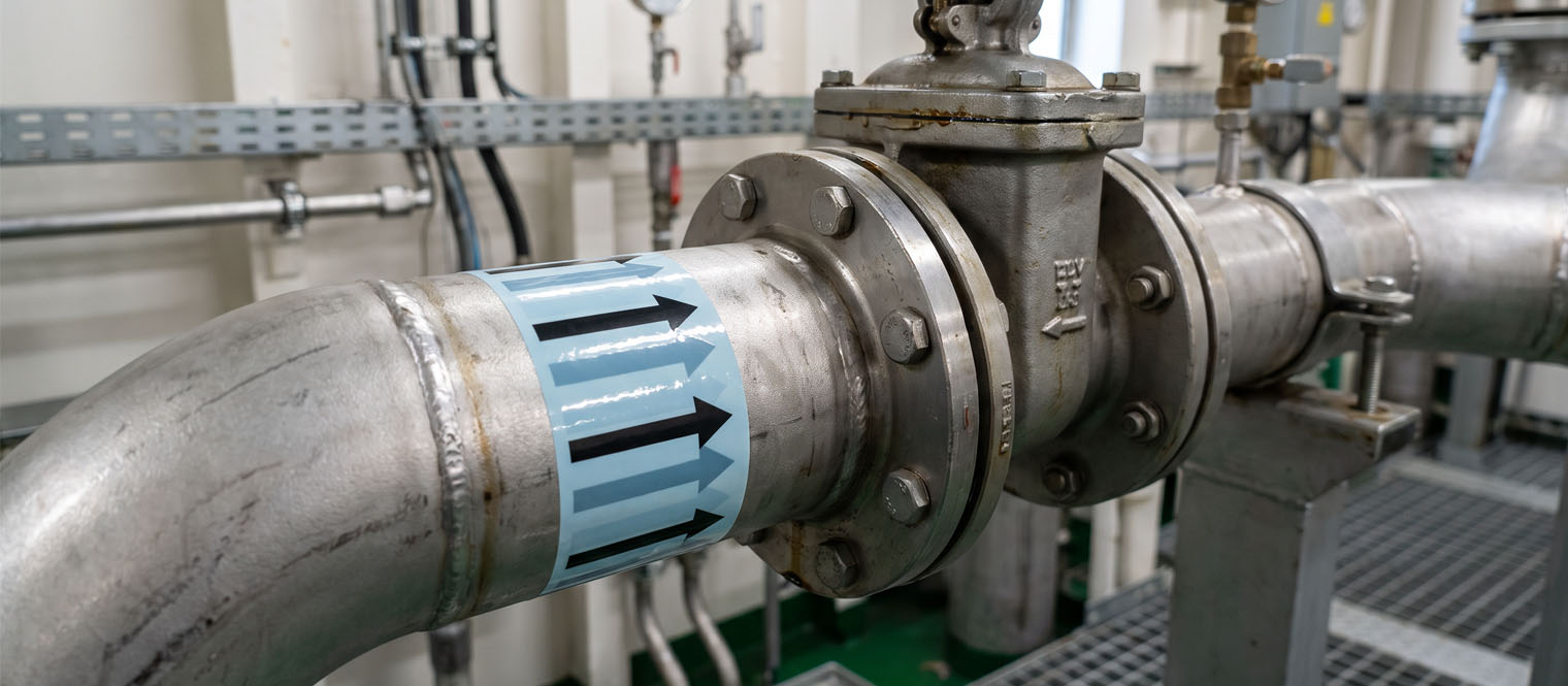 Colour-coded pipe identification marking on shipboard pipework near a valve or branch.